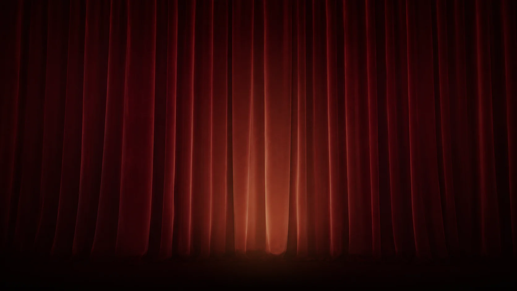 Burgundy theater curtains glowing with warm light before the show